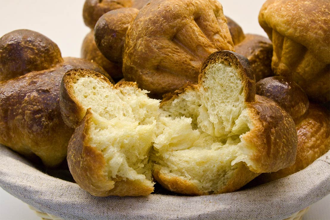a basket of the finished brioche buns with one torn open
