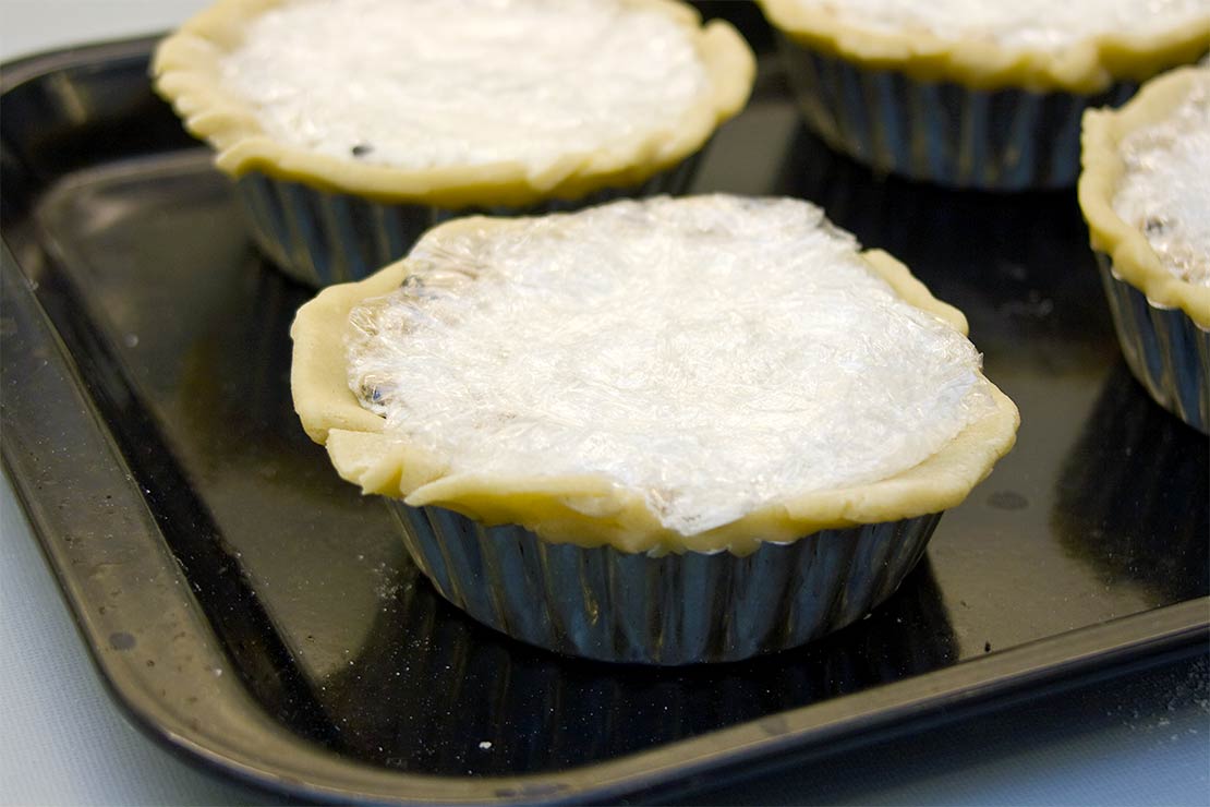 filling the pastry with baking beans