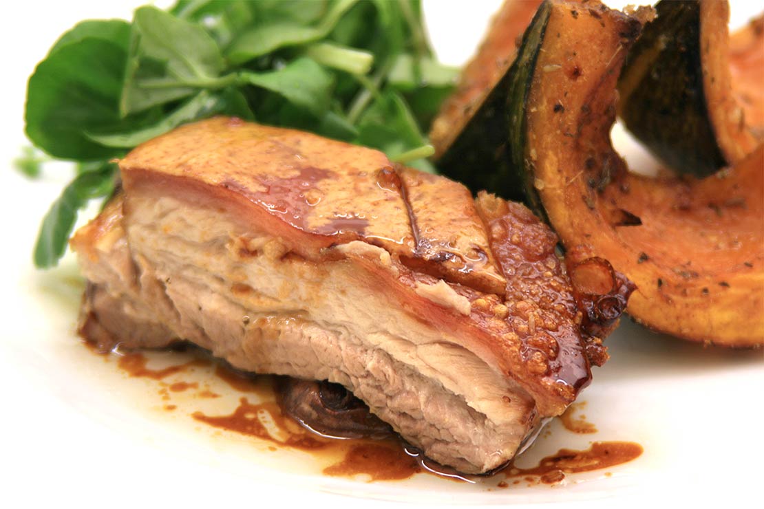 a slice of the finished slow roast pork belly