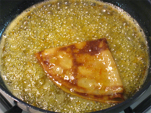 a folded crêpe in the sauce in the frying pan